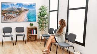 DIRECTV Remote digital out-of-home advertising screen displays luxury resort content in waiting room setting.